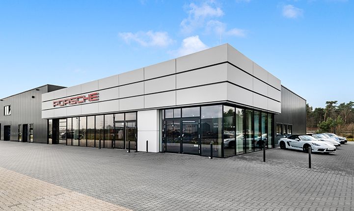 Fassade des Porsche Zentrum Emsbüren. Rechts parken Fahrzeuge. 